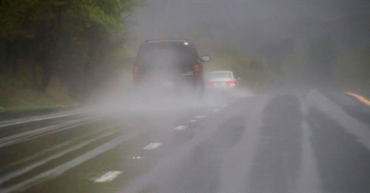 cars driving on a rainy and foggy road